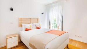 Une chambre à coucher avec un lit, une table de chevet et une fenêtre avec des rideaux.