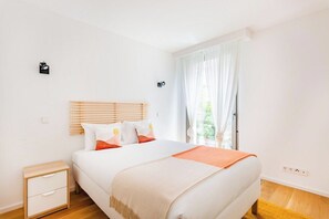 Ein Schlafzimmer mit Bett, Nachttisch und einem Fenster mit Vorhängen.