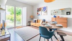 Een moderne woonkamer met een bank, eettafel, stoelen en kunstwerken.