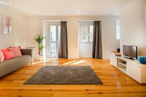 Ein Wohnzimmer mit einer Couch, einem Fernseher und einer Pflanze.