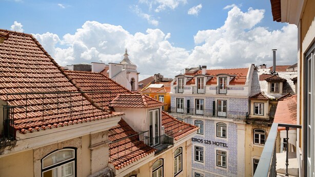 Un bâtiment historique doté d’un toit en tuiles, d’un clocher et d’une enseigne indiquant « EIROS 125 HOTEL ».