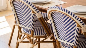 Un coin repas comprenant une table en bois, quatre chaises dotées d’un revêtement à motifs et deux verres à vin.