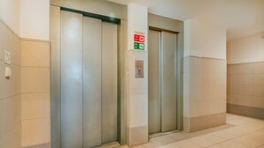 Two elevator doors in a hallway with a fire alarm sign above them. - Olaias Park Flat (Lisbon)