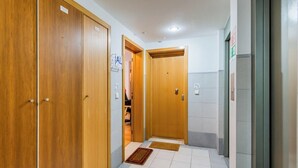 A hallway with wooden doors, a tiled floor, and a small rug. - Olaias Park Flat (Lisbon)