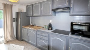 Una cocina moderna con gabinetes grises, un refrigerador de acero inoxidable, una cafetera y un horno empotrado.