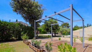 A garden with a wooden deck, metal pergola, and various plants. - Amazing home in Lauris (Lauris)