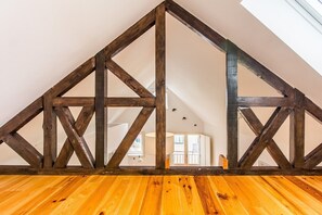 Ein Zimmer mit schrägen Deckenbalken und Holzboden.