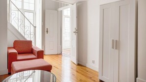 A room with a staircase, a red sofa, a glass table, and white doors. - Downtown Chiado Treasure (Lisbon)