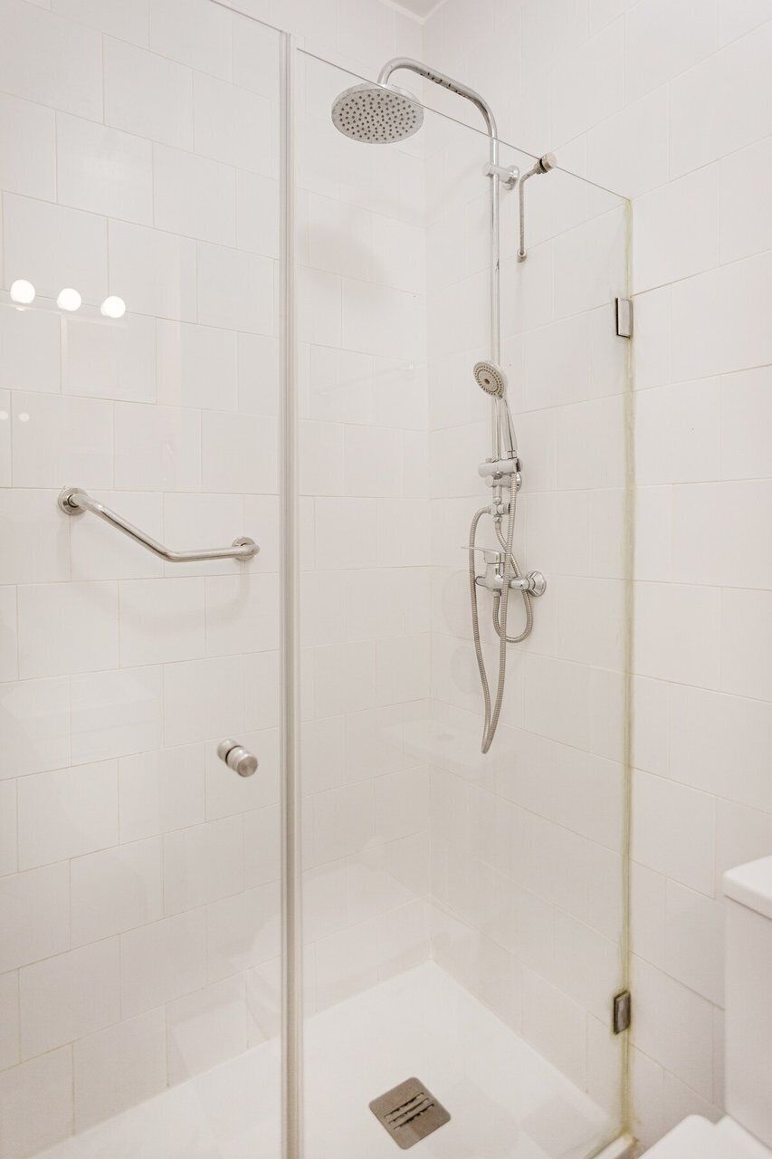 Een douchecabine met glazen wanden, een wandmengkraan en een handdouche.