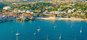 An aerial view of a coastal town with a marina, buildings, and a beach. - Alapraia Garden & Family Stay | Estoril (Estoril)