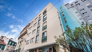 Un edificio de varios pisos con balcones, una entrada visible y cielo despejado.