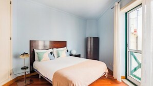 Un dormitorio con cama, lámpara de noche y vistas al exterior.