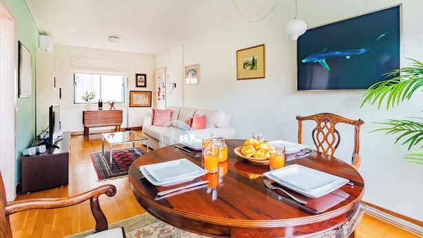 Un comedor con una mesa redonda de madera, sillas y una disposición para el desayuno, incluyendo croissants y zumo de naranja.