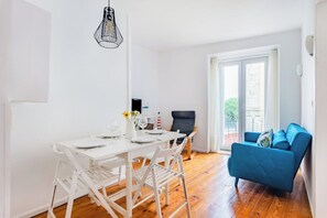 Ein Zimmer mit Esstisch für vier Personen, einem blauen Sofa und einem großen Fenster mit Aussicht.