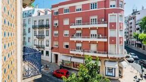 A multi-story building with balconies, a red facade, and a street view. - Conde 3BDR Luxury with Balcony (Lisbon)