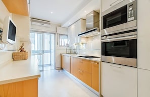 Eine moderne Küche mit Edelstahlgeräten, einem großen Fenster und einem Korbwäscheschale auf der Arbeitsplatte.