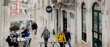 Une rue étroite, pavée de pierres, bordée d’immeubles dotés de balcons et offrant des terrasses pour les cafés.
