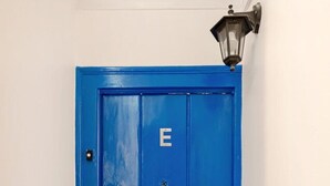 Una puerta azul con la letra 'E', una lámpara de pared y un suelo de madera.