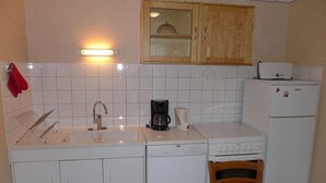 A compact kitchen with a sink, a coffee maker, a toaster, and a refrigerator.