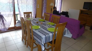 A dining area with a table set for four, wooden chairs, and a purple sofa. - Vétus Villa - Viéville - Vacation Rental (Viéville)