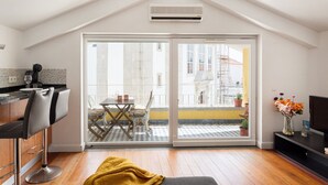 A modern kitchen with a dining area, a large sliding glass door leading to an outdoor balcony, and a TV on the right. - Yellow Suites Duplex @ Cascais Historical Center (Cascais)