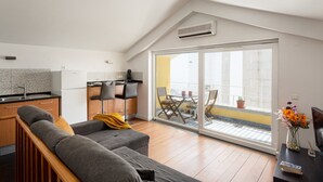 A modern apartment with a kitchen, a dining area with a table and chairs, a sofa, and a balcony with potted plants. - Yellow Suites Duplex @ Cascais Historical Center (Cascais)