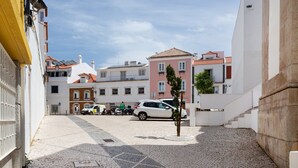 A cobblestone street with buildings, a parked car, and a person walking. - Yellow Suites Duplex @ Cascais Historical Center (Cascais)