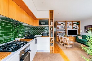 Eine moderne Küche mit grünen Fliesen, Holzschränken und einer eingebauten Mikrowelle.