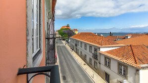 Vista de una calle con edificios, cielo despejado y una lejana vista al mar.