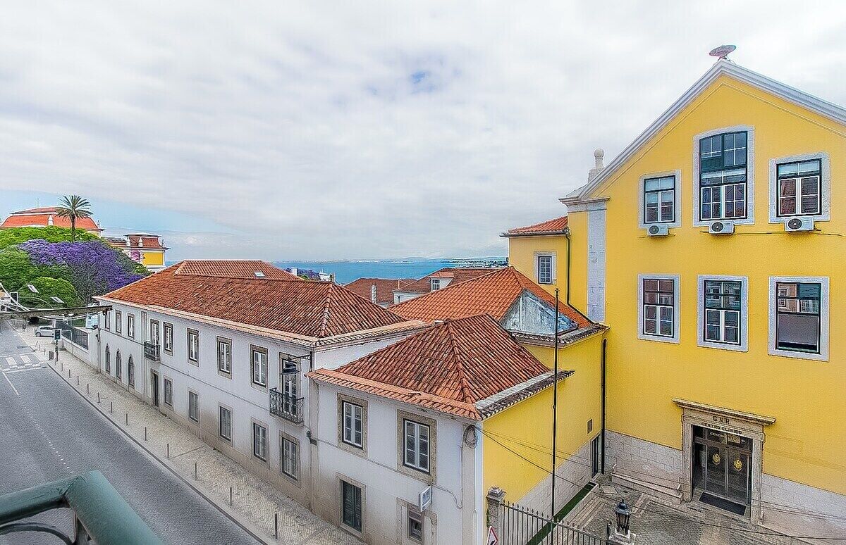 A coastal town with buildings featuring red-tiled roofs and a yellow building with multiple windows.