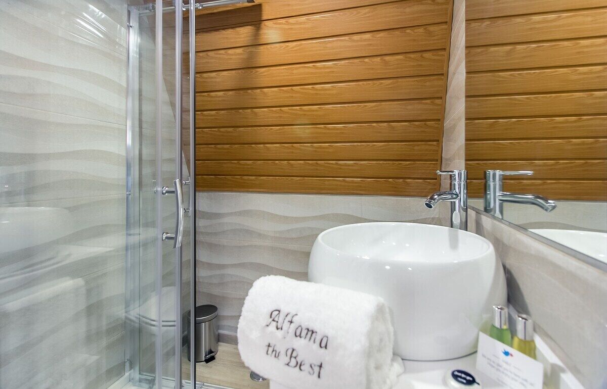 Une salle de bain moderne avec une douche à parois de verre, un lavabo blanc et un mur recouvert de panneaux en bois.