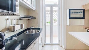 Eine moderne Küche mit schwarzer Arbeitsplatte, Spüle aus Edelstahl und einer Glastür zum Außenbereich.