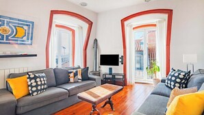Ein Wohnzimmer mit einer Couch, einem Couchtisch, einem Fernseher und einer Topfpflanze.