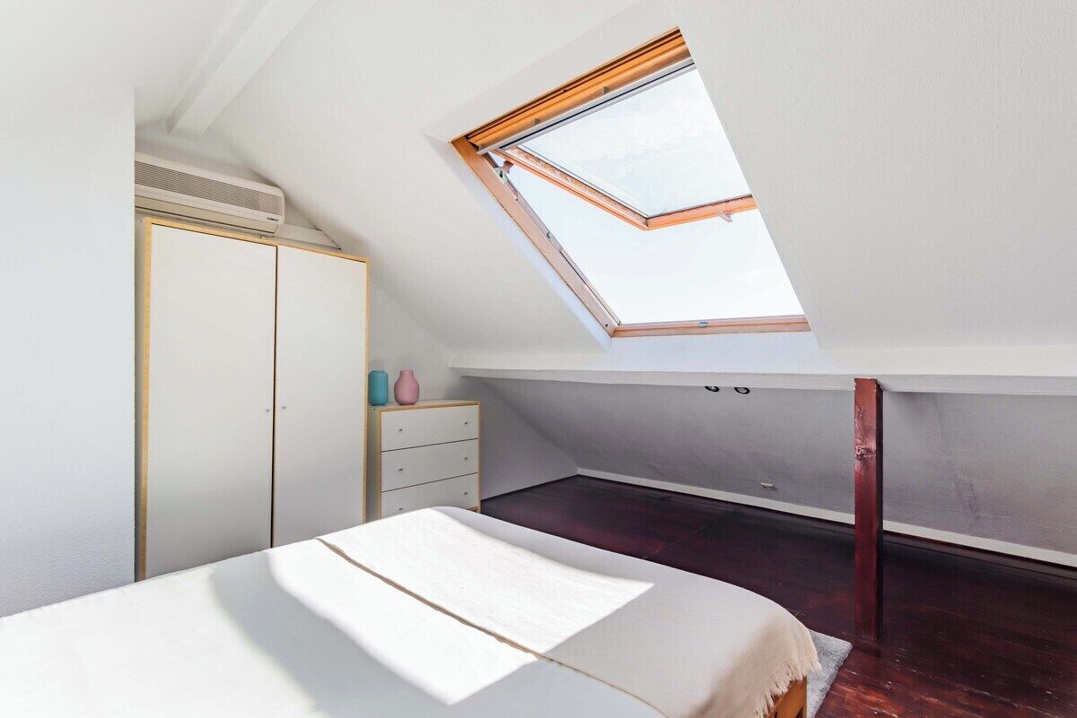 Une chambre à coucher avec un puits de lumière, un lit, une commode et une armoire.