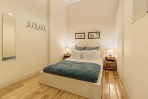 Ein Schlafzimmer mit einem Bett, Nachttischen, einem Spiegel und Wandbildern.