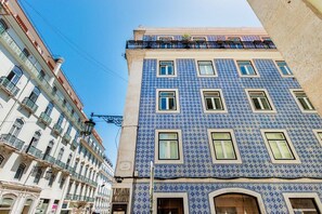 Ein mehrgeschossiges Gebäude mit einer Fassade aus blauen und weißen Fliesen, zahlreichen Fenstern und Balkonen.