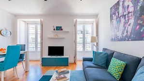 A modern living room with a sofa, a TV, a dining area with chairs, and a bookshelf. - Lisbon Prime Apartment (Lisbon)