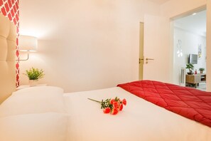 Ein Hotelzimmer mit Bett, Nachttischlampe, einer kleinen Pflanze und einem Blumenstrauß.