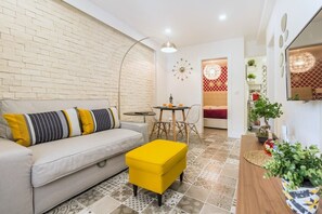 Ein Wohnzimmer mit Sofa, Hocker und einem Essbereich mit Stühlen und Tisch.