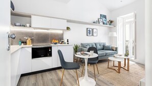 Ett kompakt bostadsutrymme med ett litet kök, en soffa, två stolar och ett litet matbord.