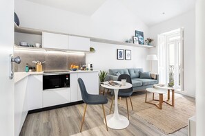 A compact living space with a kitchenette, a sofa, two chairs, and a small dining table. - Studio Mar, in the Heart of Lisbon (Lisbon)