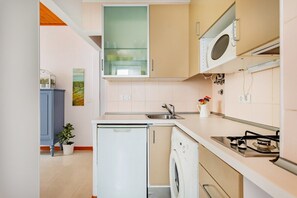 Eine kleine Küche mit Kühlschrank, Waschmaschine, Mikrowelle und Gasherd.