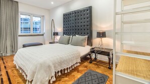 Ein modernes Schlafzimmer mit einem großen Bett, Nachttischen, einem Fenster und einer integrierten Regallösung.