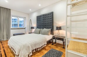 Ein modernes Schlafzimmer mit einem großen Bett, Nachttischen, einem Fenster und einer integrierten Regallösung.