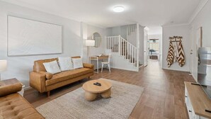 Una sala de estar moderna con un sofá, una mesa de centro y una escalera que conduce a otra habitación.