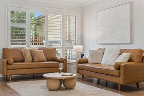 Ein Wohnzimmer mit zwei braunen Sofas, einem runden Couchtisch und einem großen, abstrakten Gemälde an der Wand.