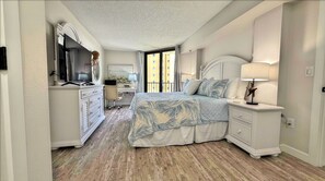 A bedroom with a bed, nightstands, a dresser, a desk, and a chair. - Quintessential Beachfront Condo escape right on the Sand with private balcony (New Smyrna Beach)