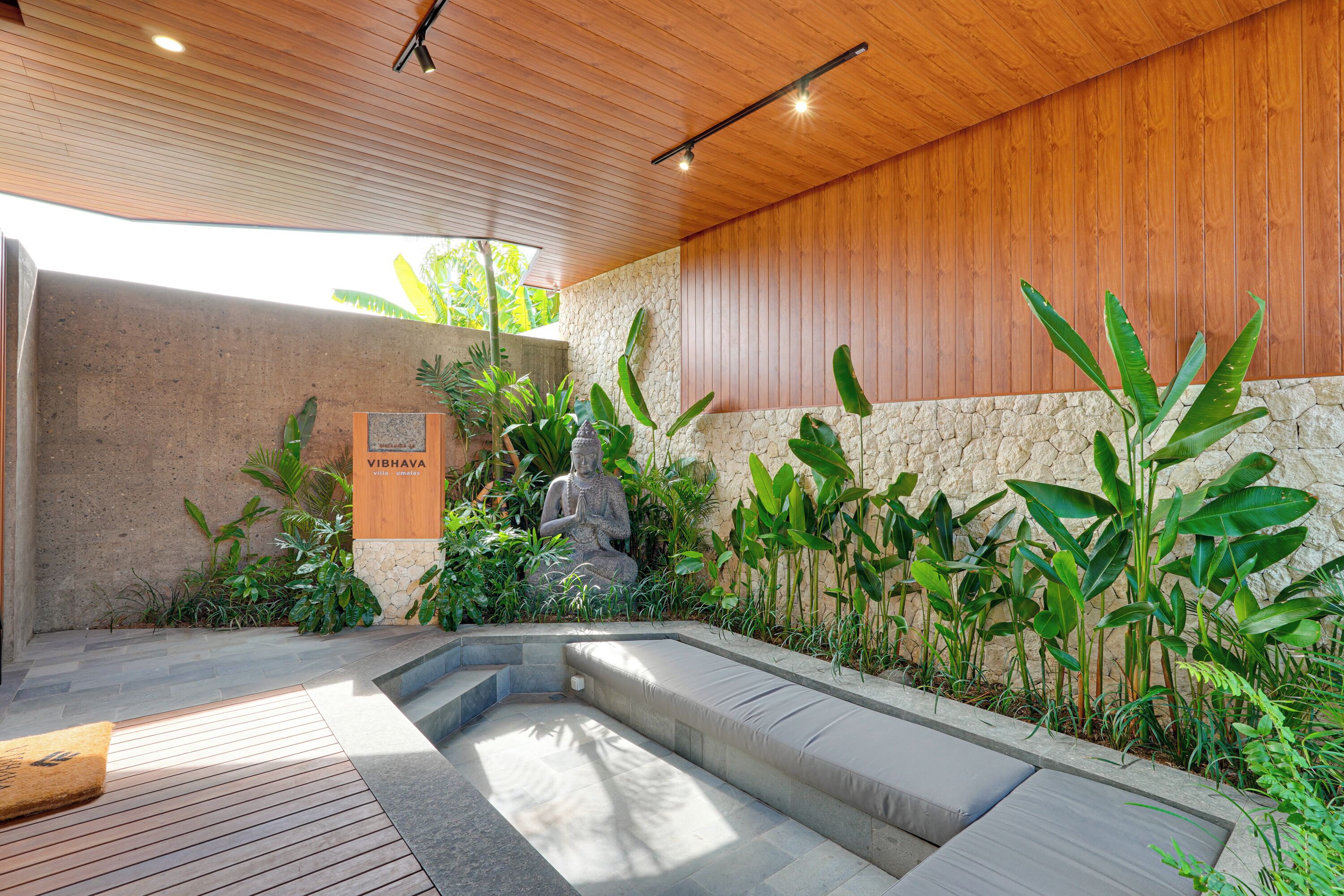 A spa area with a stone wall, wooden ceiling, and a statue.