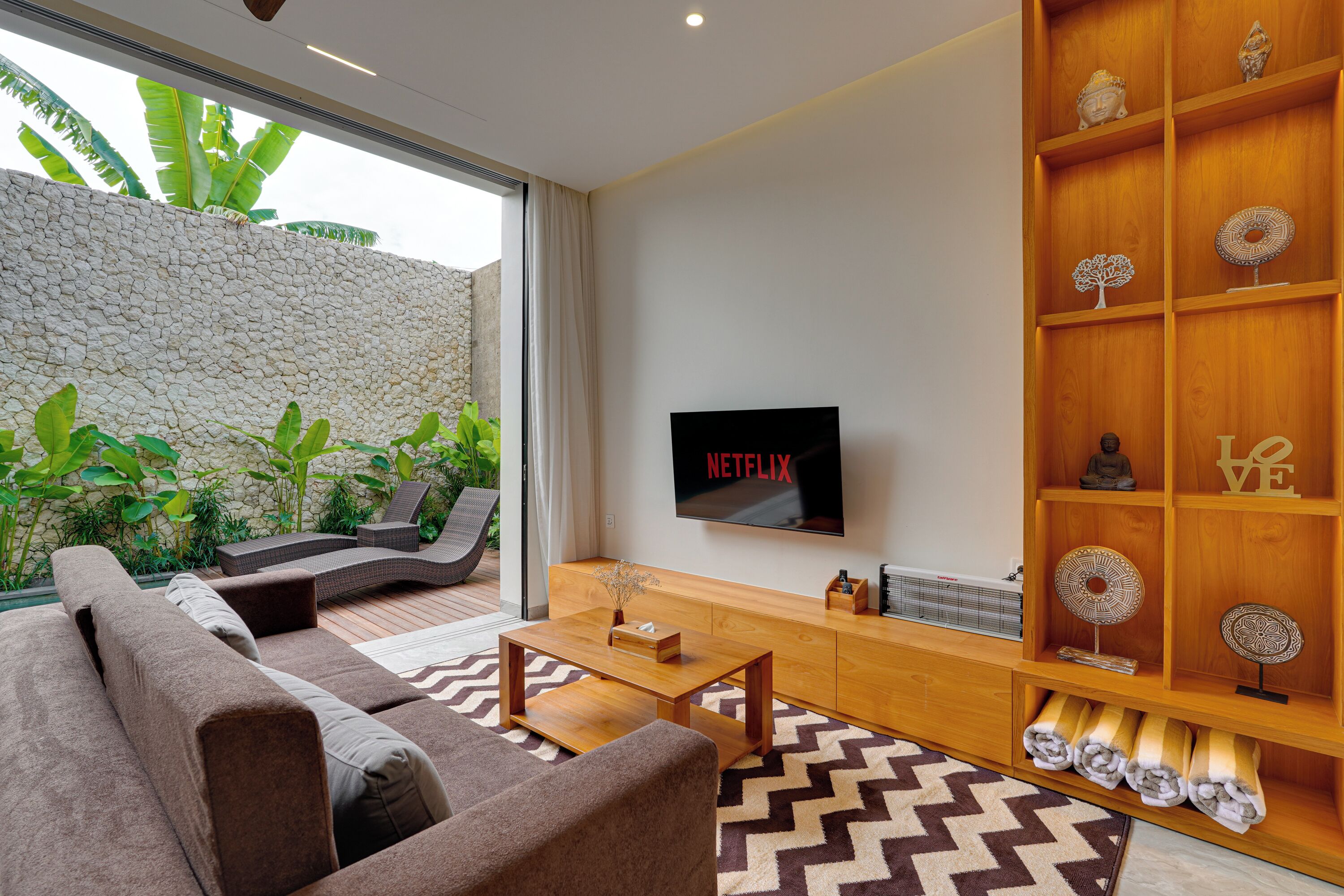 A modern living room with a sofa, coffee table, and a TV mounted on the wall.