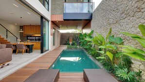 A modern house with a swimming pool, wooden deck, and a balcony overlooking the pool. - Villa Vibhava - Umalas (Seminyak)